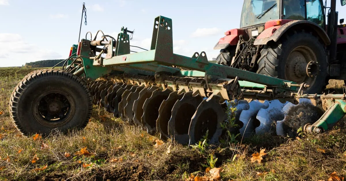 Agricultural cultivator working the soil with cultivator blades during land preparation.